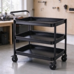 Empty black utility cart in a workshop with a pegboard wall